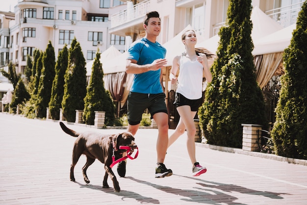 Le coppie stanno correndo sulla strada con il grande cane