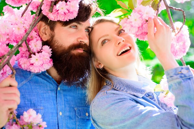 Le coppie stanno vicino alla coppia dell'albero di sakura nella soleggiata giornata primaverile uomo e donna nella coppia di giardini fioriti