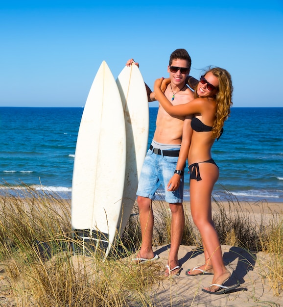 Le coppie teenager dei surfisti abbracciano sulla spiaggia