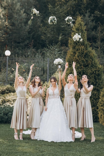 Le damigelle d'onore in abiti color pastello sono in piedi vicino alla sposa all'aperto.