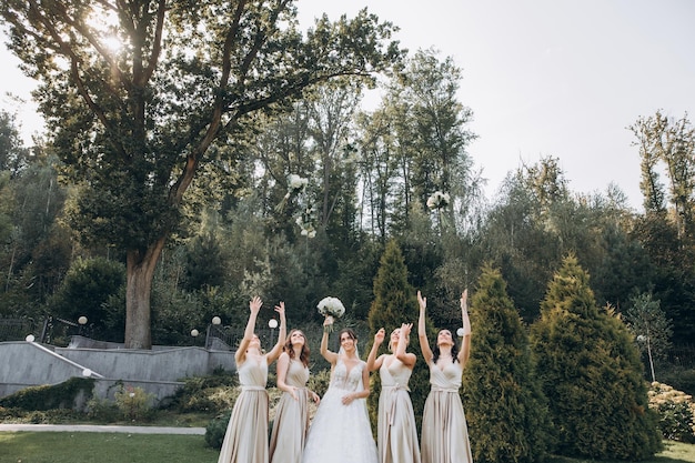 Le damigelle d'onore in abiti color pastello sono in piedi vicino alla sposa all'aperto.