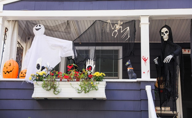 Le decorazioni di Halloween adornano il cortile anteriore di una casa infestata con zucche, fantasmi e ragnatele.