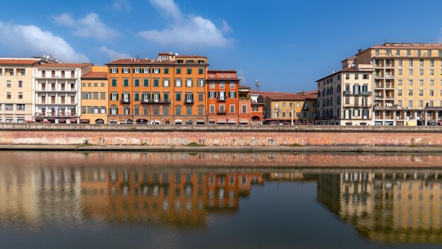 Le dighe del fiume Arno con gli edifici residenziali della vecchia città si riflettono nell'acqua di giorno a Pisa, in Italia