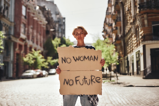 Le donne alimentano la giovane donna che tiene un cartello con la parola nessuna donna nessun futuro in piedi