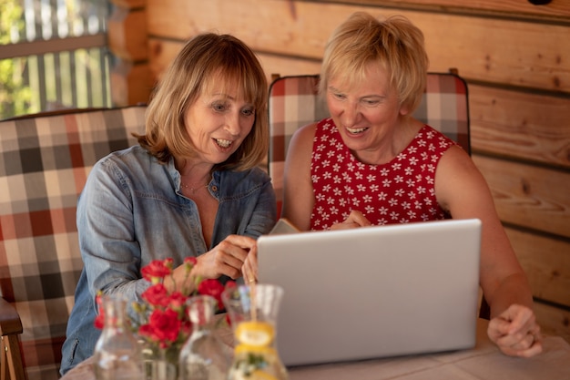 Le donne anziane di amici di lunga data ridono insieme mentre guardano il computer portatile, a casa.