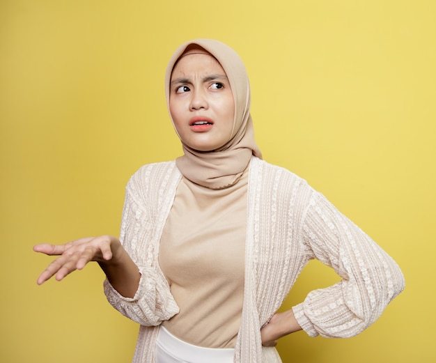 Le donne asiatiche hijab parlano chiedendo. espressione confusa. isolato su uno sfondo giallo