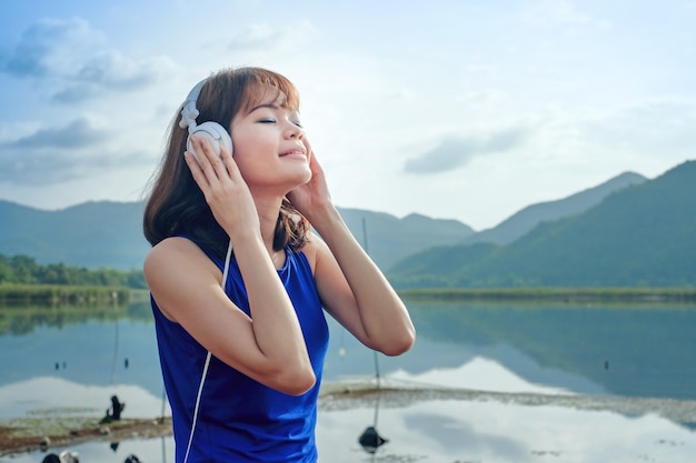 Le donne asiatiche indossano una camicia sportiva con le cuffie ascoltando musica e rilassandosi all&#39;aria aperta