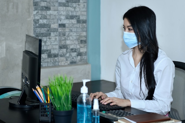 Le donne asiatiche lavorano a casa. Per confinarsi durante il virus corona Indossando una maschera e lavandosi le mani disinfettando per prevenire Covid-19