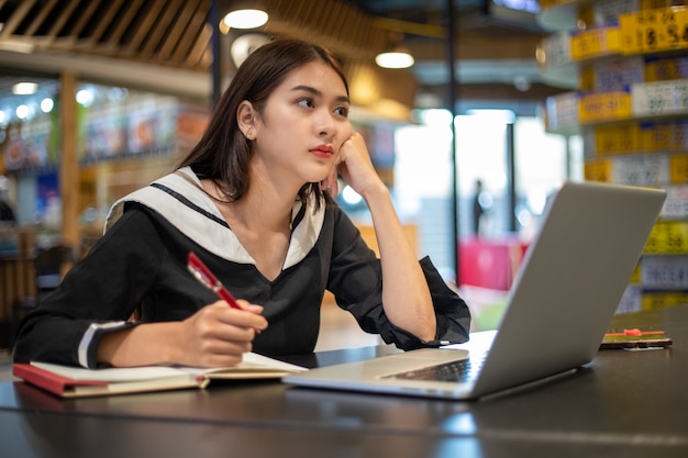 Le donne asiatiche si sentono seriamente a lavorare e studiare online con i computer portatili.