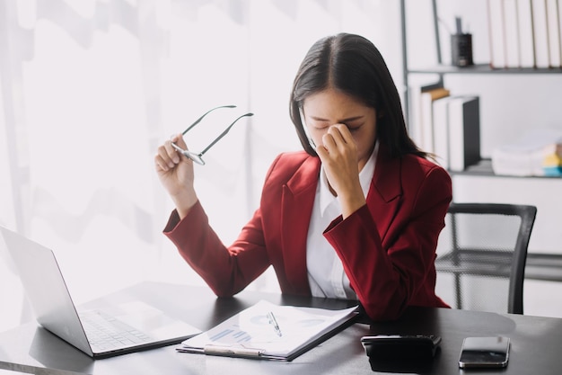 Le donne asiatiche sono stressate mentre lavorano sul laptop Donna d'affari asiatica stanca con mal di testa in ufficio che si sente male al lavoro spazio di copia