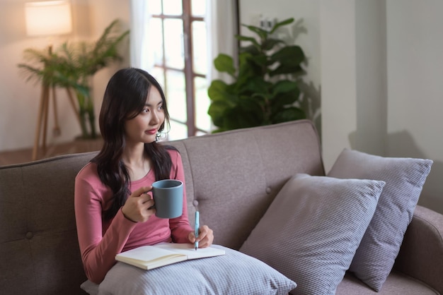 Le donne che guardano fuori si divertono sognando mentre bevono il tè e scrivono un diario nello stile di vita di casa