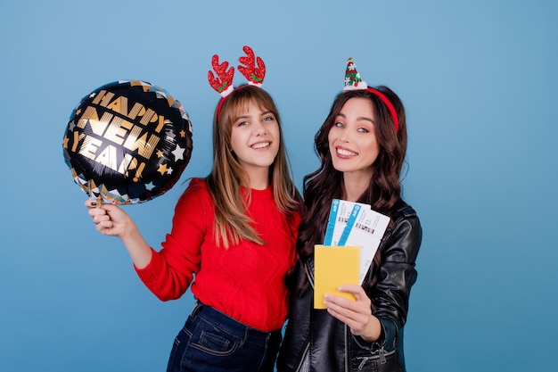 Le donne con i biglietti di aeroplano e l'aerostato del buon anno isolati sopra il blu