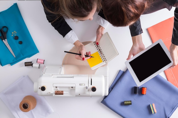 Le donne con tablet e notebook stanno per iniziare a cucire