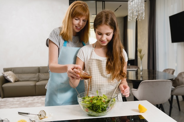 Le donne di famiglia versano il condimento per l'insalata insieme in casa