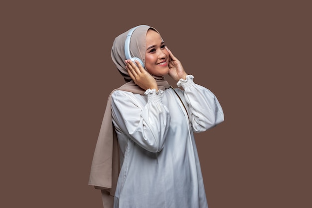 le donne felici con l'hijab che usano le cuffie wireless si divertono ad ascoltare musica