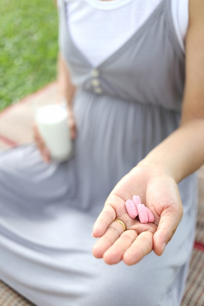 Le donne incinte hanno un bicchiere di latte e vitamina in mano per mangiare.