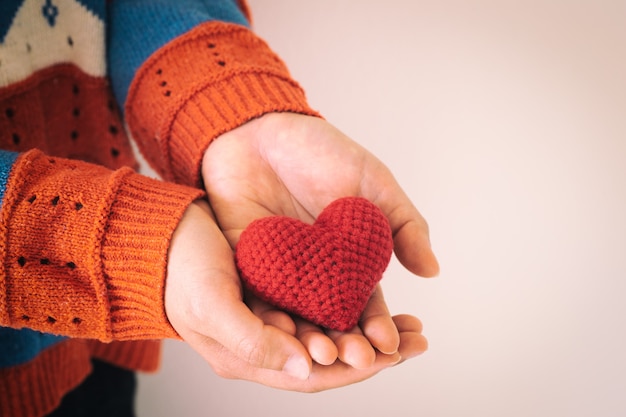 Le donne indossano la mano della camicia lavorata a maglia che tiene il cuore rosso.
