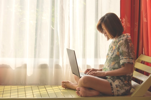 Le donne lavorano con i notebook sul letto in legno Sfondo bianco tende e luce naturale.