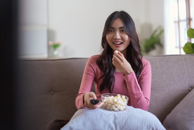 Le donne mangiano popcorn e cambiano canale con il telecomando mentre guardano la tv nello stile di vita di casa