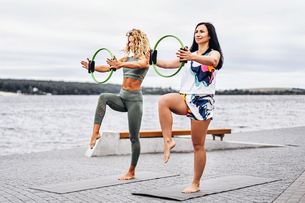 le donne praticano esercizi di yoga su una stuoia con uno speciale circolo sportivo