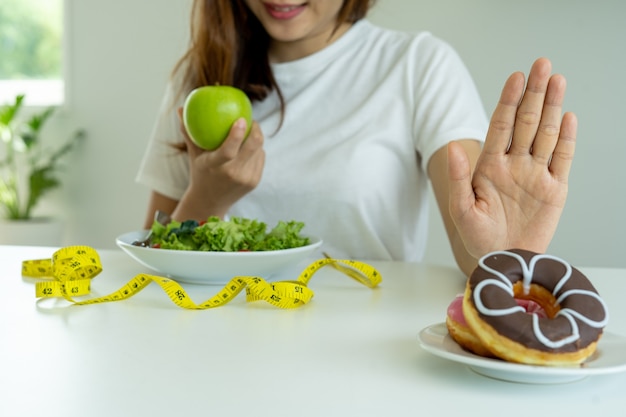 Le donne rifiutano il cibo spazzatura o cibi malsani come le ciambelle e scelgono cibi sani come mele verdi e insalate.