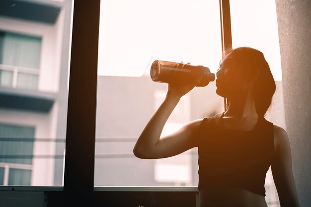 Le donne sane bevono proteine del siero di latte e si rilassano dopo una sessione di allenamento nella palestra al coperto per rilassarsi dopo l'esercizio.