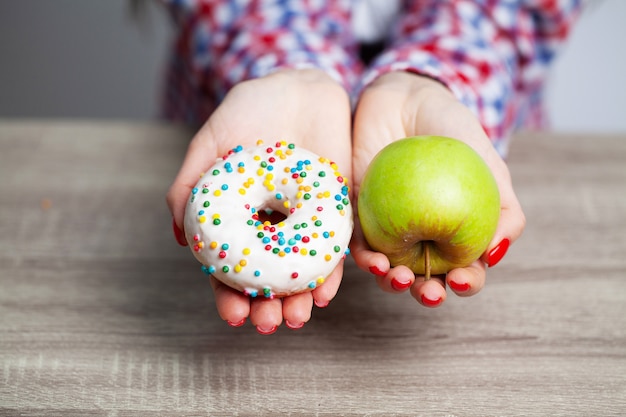 Le donne scelgono la scelta tra ciambella e mela verde durante la sua sessione di dieta