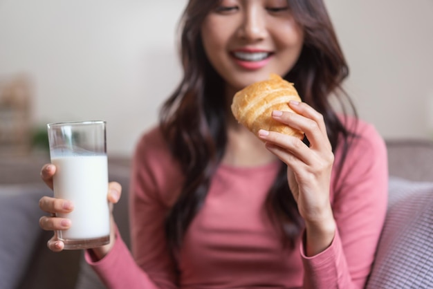 Le donne si divertono sul divano a bere latte e mangiare pane con un pasto sano nello stile di vita di casa