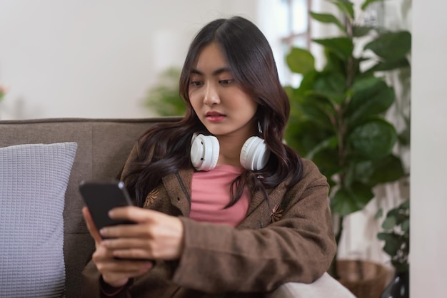 Le donne si divertono sul divano, navigano sui social media e si divertono sullo smartphone nello stile di vita di casa