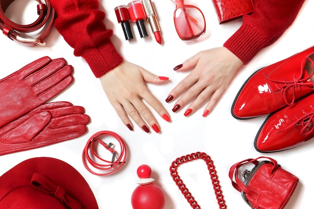 Le donne sono mani con una manicure rossa e una collezione di accessori con capi di abbigliamento