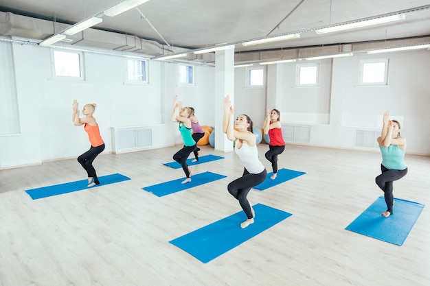 Le donne stanno praticando esercizi di yoga in studio itness sport persone e concetto di stile di vita sano