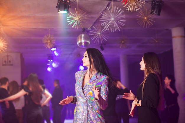 Le due ragazze stanno ballando in una discoteca sullo sfondo della folla