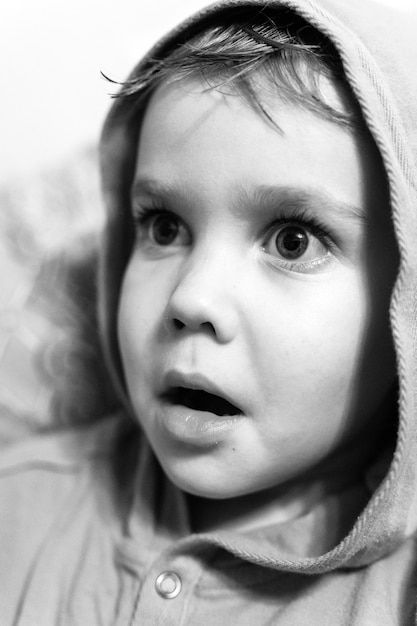 Le emozioni candide dei bambini sul viso. ritratto di un ragazzino con un'espressione di sorpresa o paura sul viso. occhi e bocca spalancati. colorato in bianco e nero. effetto rumoroso e grana
