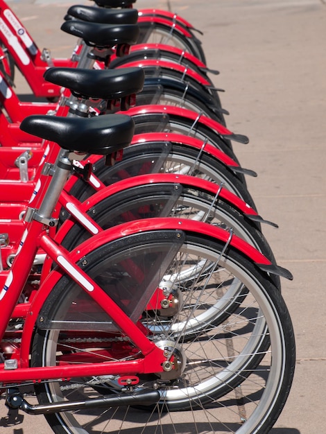 Le file di biciclette rosse che vengono utilizzate per il noleggio per spostarsi a Denver sono sia utili per il divertimento che per l'esercizio fisico, ma anche utili per l'ambiente in quanto risparmiano sull'uso dell'auto e sul gas, sul traffico e sui gas di scarico.