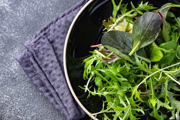 Le foglie di insalata verde sane mescolano micro spuntini verdi e succosi sul cibo dello spazio della copia del tavolo