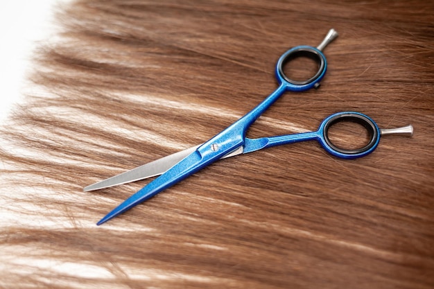 Le forbici giacciono sul nastro dei capelli per l'estensione a casa. Estensioni dei capelli per ispessire le tue.