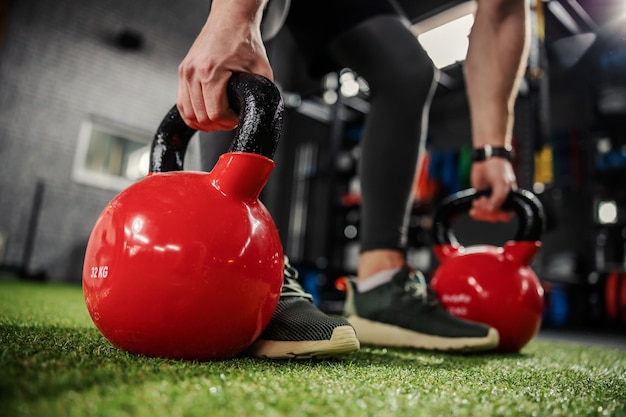 Le forti braccia maschili prendono l'attrezzatura sportiva per l'esercizio e si preparano a sollevare pesi