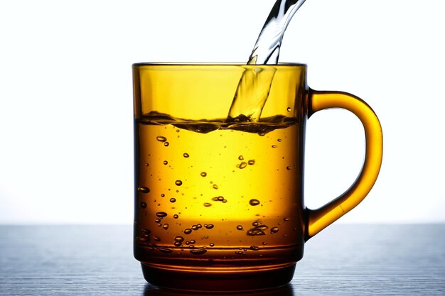 Le foto versano l'acqua in un tè o in un bicchiere marrone