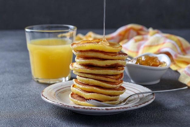 Le frittelle di latte vengono versate con sciroppo dolce e servite a colazione con succo d'arancia