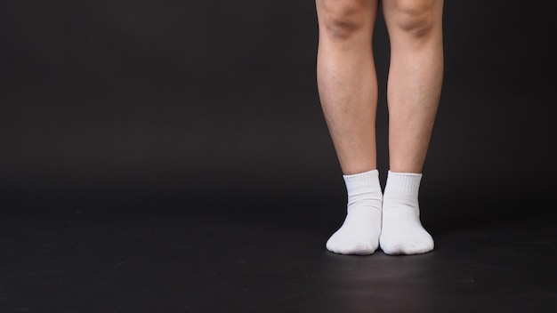 Le gambe asiatiche maschili indossano un calzino bianco isolato su sfondo nero