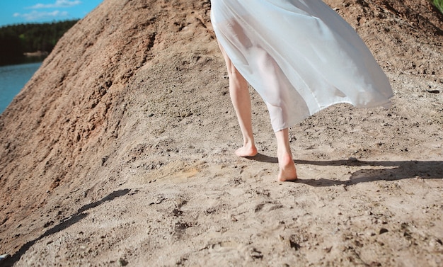 Le gambe bianche del vestito chiaro della ragazza eseguono la molla