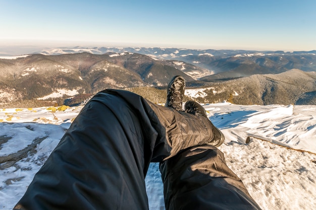 Le gambe degli uomini in scarpe invernali contro il panorama sulle montagne dei Carpazi.