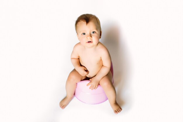 Le gambe dei bambini che pendono da un vaso da notte su uno sfondo bianco