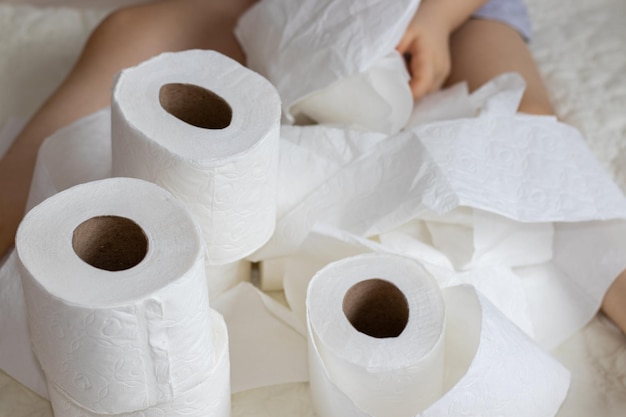 le gambe del bambino o del neonato sul letto avvolte con rotoli di carta igienica bianca hanno bisogno del concetto di igiene durante
