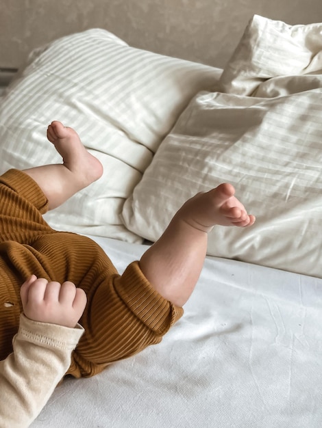 Le gambe del bambino sollevate e la maniglia sul letto con il comfort domestico dei cuscini