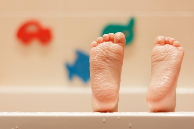 Le gambe del bambino sono rugose per una lunga permanenza in acqua sullo sfondo di un muro