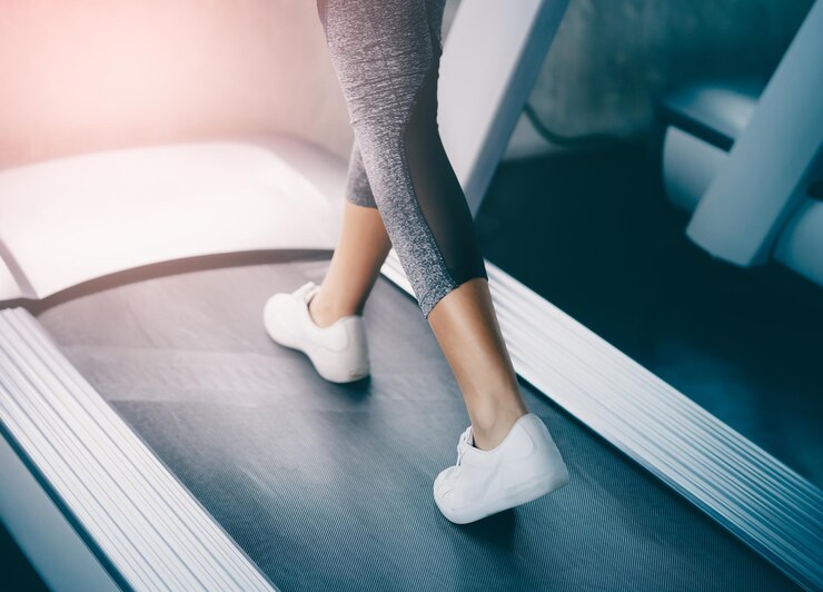 Le gambe del corridore indoor stanno camminando lentamente sul tapis roulant per un esercizio leggero ravvicinato