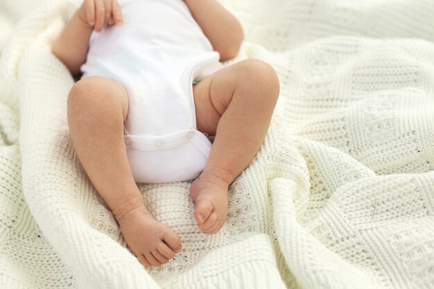 Le gambe del piccolo bambino sulla coperta bianca
