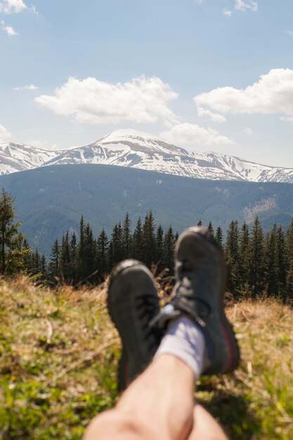 Le gambe del viaggiatore seduto su una cima di alta montagna in viaggio