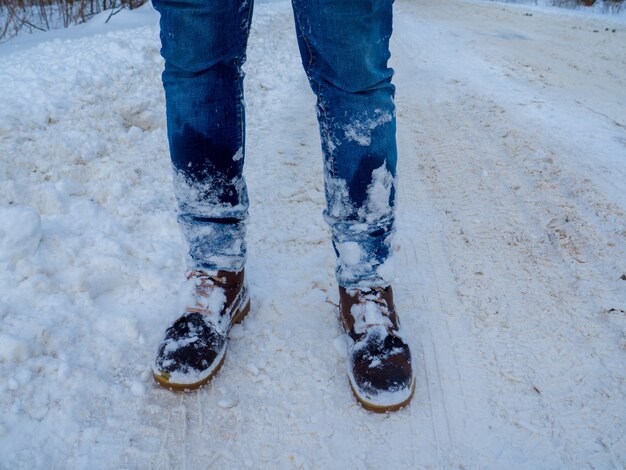 Le gambe dell'uomo con gli stivali marroni restano nella neve